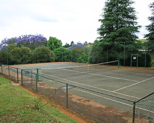 An outdoor tennis court surrounded by trees.