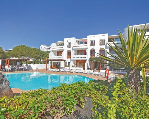 An outdoor swimming pool with chaise lounge chairs and patio furniture alongside resort units.