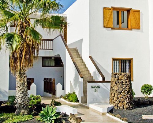 An exterior view of the resort unit with a staircase and a palm tree.