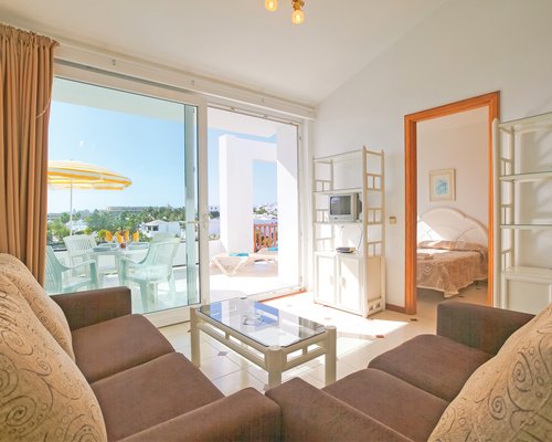 An open plan living room with television bedroom and an outside view.