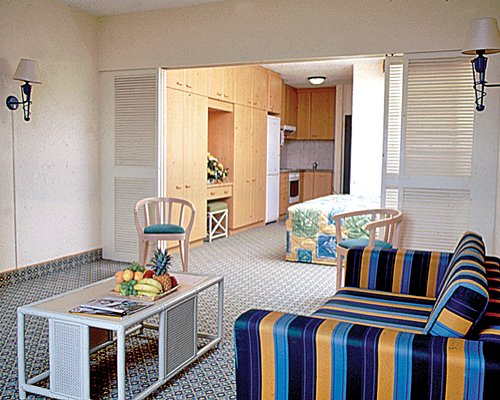 A well furnished living room with open plan kitchen and twin bed.