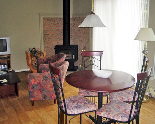 A well furnished living room with television and fireplace alongside the dining table.