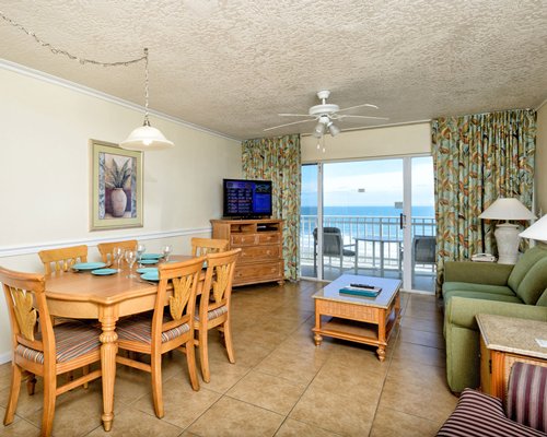 An open plan living and dining area with a television and beach view.