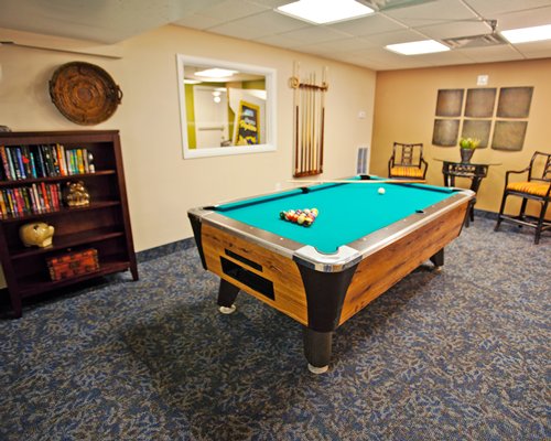 Indoor recreation room with pool table and book shelf.