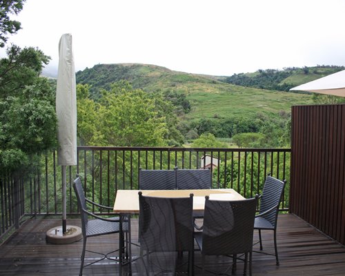 A balcony with a dining table with the view of hills.