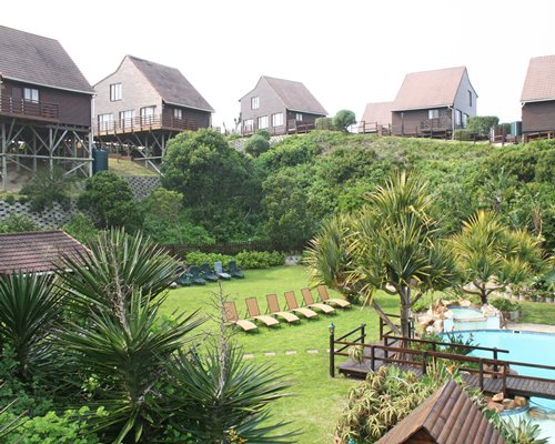Scenic outdoor swimming pool with chaise lounge chairs alongside multi story resort units.