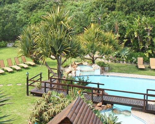 Outdoor swimming pool with a pathway and chaise lounge chairs.