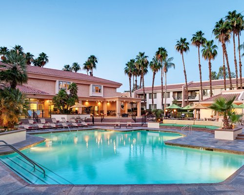 An outdoor swimming pool with chaise lounge chairs alongside the resort units.