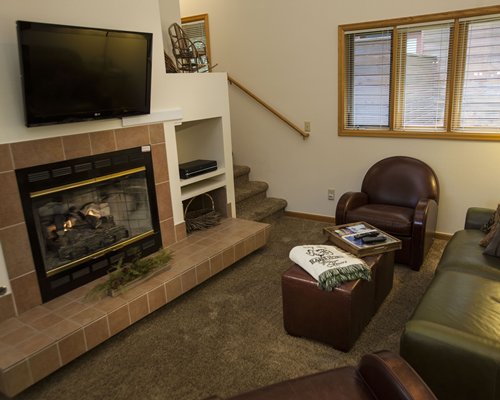 A well furnished living room with a television stairway and fire in the fireplace.