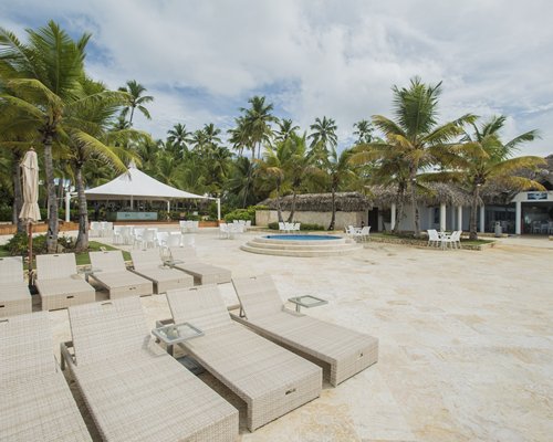 A beach with chaise lounge chairs alongside resort units and trees.
