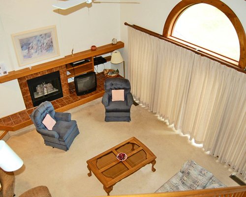 View of well furnished living room with television and fireplace from indoor balcony.