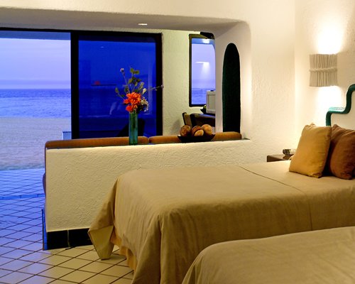 A well furnished bedroom with two twin beds alongside the beach.