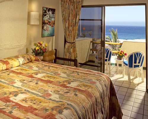 A well furnished bedroom with king bed balcony patio furniture and ocean view.