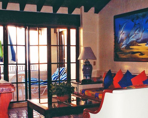 A well furnished living room alongside a balcony with chaise lounge chair.