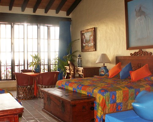 A well furnished bedroom with king bed dining area and outside view.