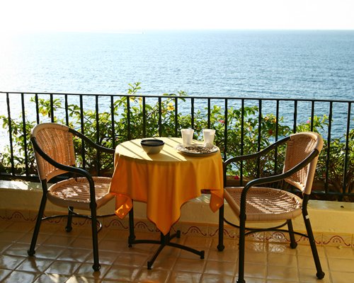 A balcony with patio furniture alongside the ocean.
