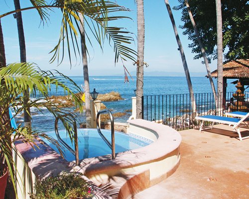 An outdoor hot tub with chaise lounge chairs facing the beach.