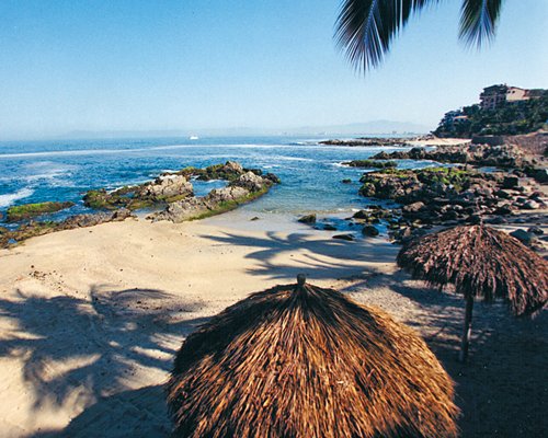 A beach with thatched sunshades alongside the resort.