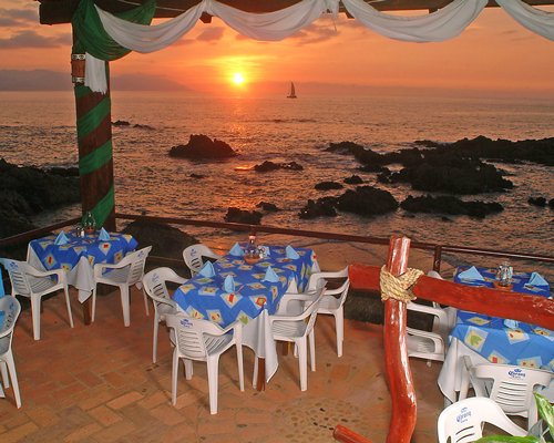 A fine dining area alongside the ocean at dusk.