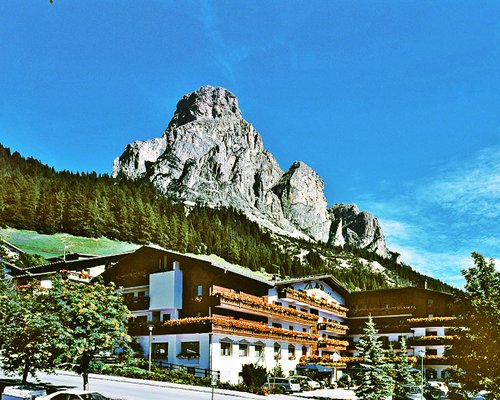 An exterior view of the Domina Home Miramonti resost alongside a mountain.