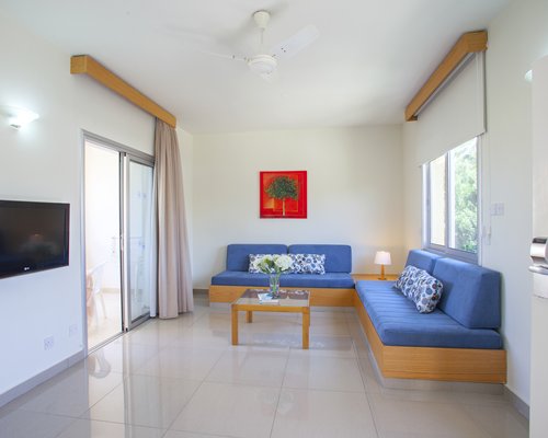 A well furnished living room with open plan kitchen breakfast bar television and outside view.