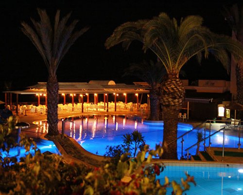 An outdoor swimming pool alongside a restaurant at night.