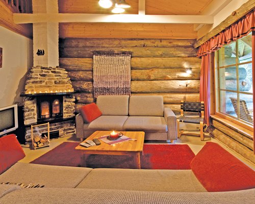 A well furnished living room with a pull out sofa television and fire in the fireplace.