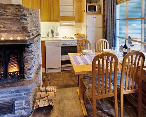 A well equipped kitchen with dining area and fire in the fireplace.