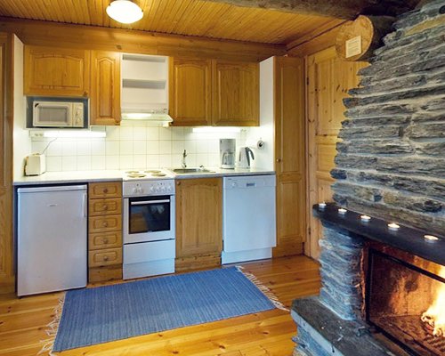 A well equipped kitchen alongside fire at the fireplace.
