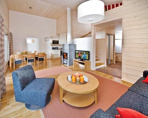 A well furnished living room with a television dining area and fire in the fire place.