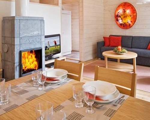 A well furnished living room with a television dining area and fire in the fireplace.
