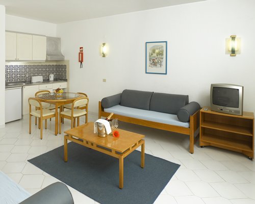 An open plan living room with a television glass top dining and kitchen area.