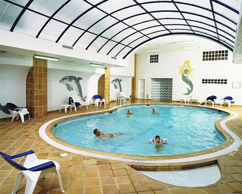 A large indoor swimming pool alongside patio furniture.