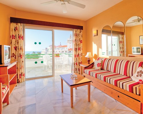 A well furnished living room with a television and balcony with patio furniture.