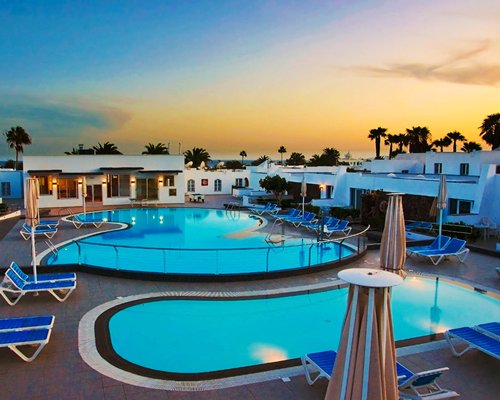 An outdoor swimming pool with chaise lounge chairs and sunshades.
