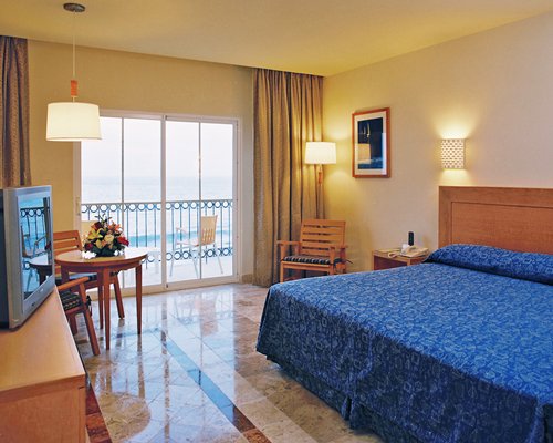 A well furnished bedroom with television and balcony view.