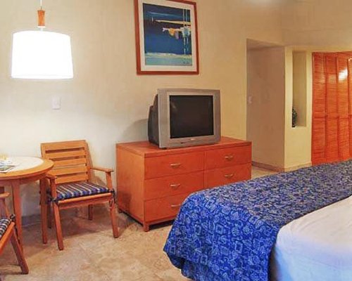 A well furnished bedroom with king bed and a television.