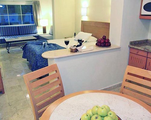 A well furnished living room with an open plan kitchen dining area and a bed.