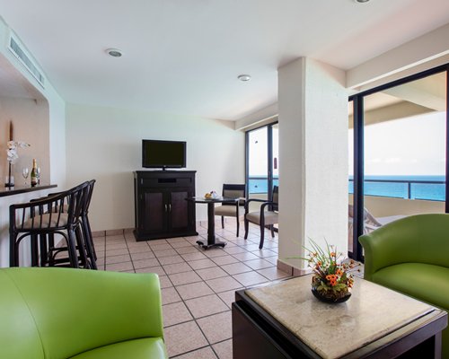 A well furnished living room with a television and balcony facing the ocean.