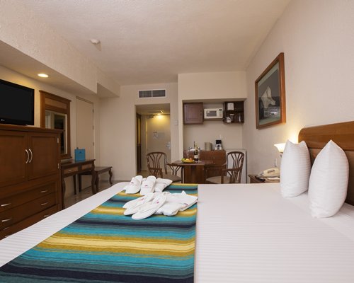 A well furnished bedroom with king bed television and dining area.