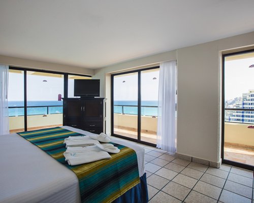 A well furnished bedroom with a television and a beach view.