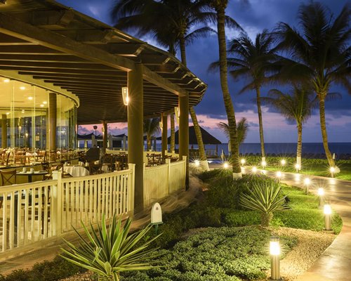 Scenic pathway and restaurant alongside the ocean at dusk.