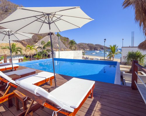 Outdoor swimming pool with a hot tub alongside multiple unit balconies.