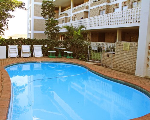 An outdoor swimming pool with lounge chairs alongside multi story resort units.