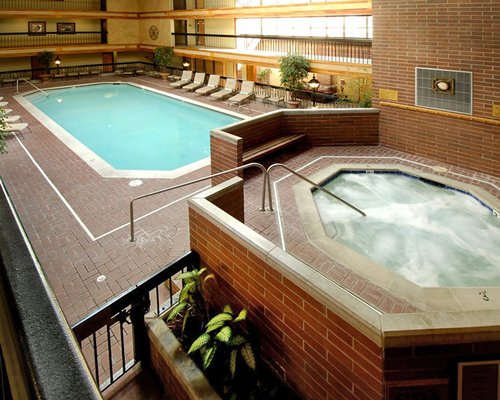 Indoor swimming pool with a hot tub and chaise lounge chairs.