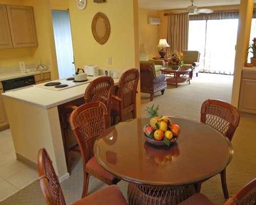 A well equipped kitchen with a dining table alongside living room.