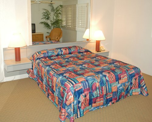 A well furnished bedroom with a queen bed and television.