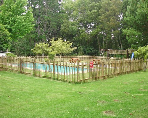 An outdoor swimming pool surrounded by lawns and trees.