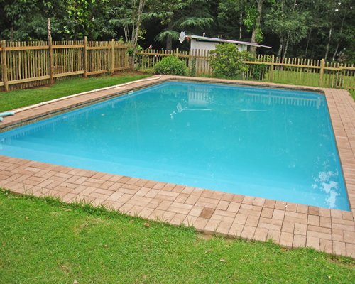 Outdoor swimming pool surrounded by wooded area.
