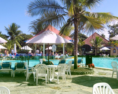 An outdoor swimming pool with chaise lounge chairs and patio furniture alongside resort units.